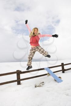 Royalty Free Photo of a Woman Jumping Excitedly in a Snowy Field With a Snowboard