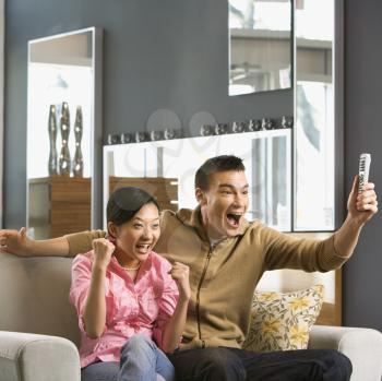 Royalty Free Photo of an Asian Couple Cheering While Watching Television