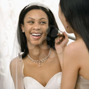 Royalty Free Photo of a Bridesmaid Applying Makeup to a Bride