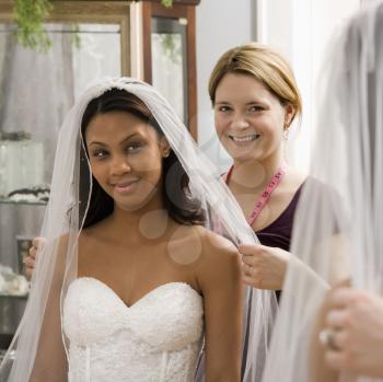 Royalty Free Photo of a Seamstress Helping an African American Bride With a Veil in a Bridal Shop