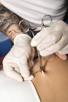 Royalty Free Photo of a Close-up of Skin Held in a Piercing Tool as a Needle is Ready to Pierce a Navel