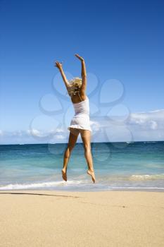 Royalty Free Photo of a Woman Jumping on Maui, Hawaii Beach With Arms Raised Into the Air