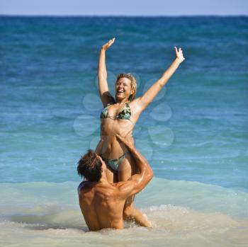 Royalty Free Photo of a Man Holding a Woman Up Out of Water on Maui, Hawaii Beach