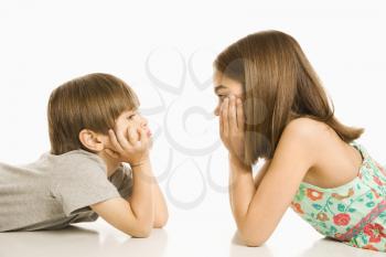 Portrait of girl and boy lying looking at eachother.