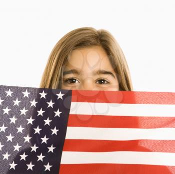 Girl peeking over American flag against white background.