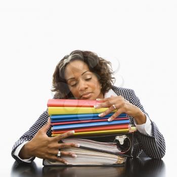 Royalty Free Photo of a Businesswoman Resting Her Head on a Large Stack of Books and Files With Her Eyes Closed