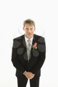 Portrait of Caucasian groom with hands clasped in front of him.