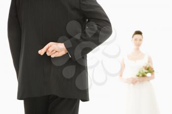 Royalty Free Photo of a Groom With His Fingers Crossed Bride in the Background