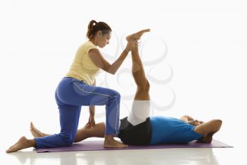 Royalty Free Photo of a Woman Assisting a Man With Stretching on an Exercise Mat