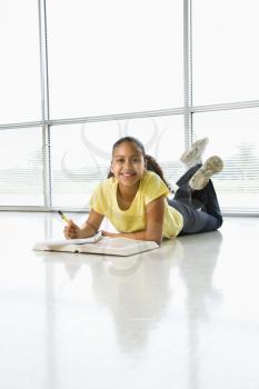 Royalty Free Photo of a Girl Lying on the Floor Doing Homework