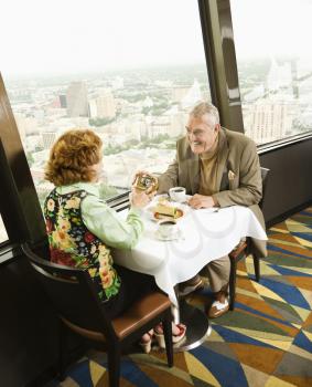 Royalty Free Photo of a Couple Having Dinner in a Restaurant as a Man Gives a Gift to a Woman