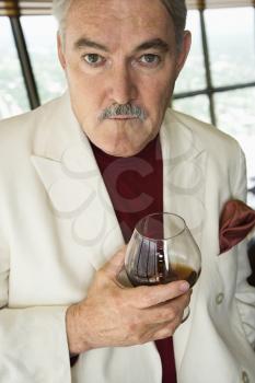Royalty Free Photo of a Mature Man in a Suit Holding a Snifter of Brandy Smiling