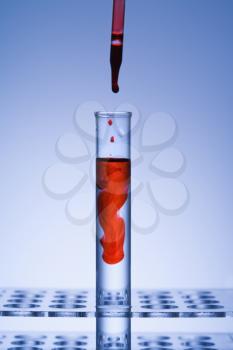 Royalty Free Photo of an Eye Dropper Dropping Red Liquid into a Glass Tube