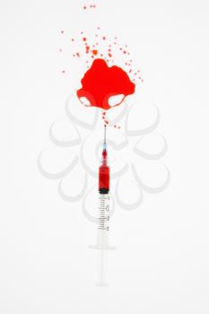 Royalty Free Photo of an Hypodermic Needle With Red Liquid Sprayed on a White Background