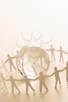 Royalty Free Photo of Cutout paper people standing around globe holding hands
