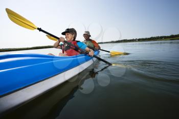 Royalty Free Photo of a Low Angle of African American Middle-aged Man and Woman Paddling Kayak