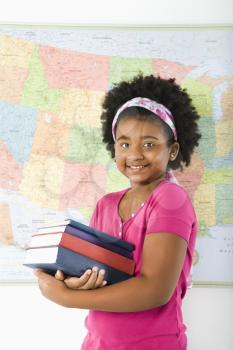 Royalty Free Photo of a Girl Standing in Front of a USA Map Holding a Stack of Books Smiling