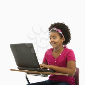 Royalty Free Photo of a Girl Sitting in a School Desk Typing on a Laptop