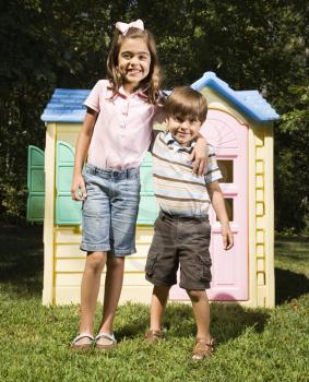Royalty Free Photo of a Brother and Sister in Front of an Outdoor Playhouse Smiling