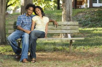 Royalty Free Photo of a Happy Smiling Couple Sitting on a Park Bench Together
