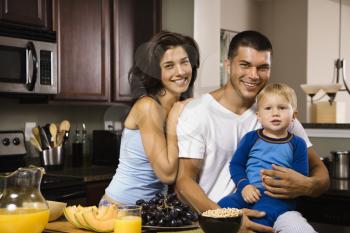 Royalty Free Photo of a Family in a Kitchen at Breakfast Smiling