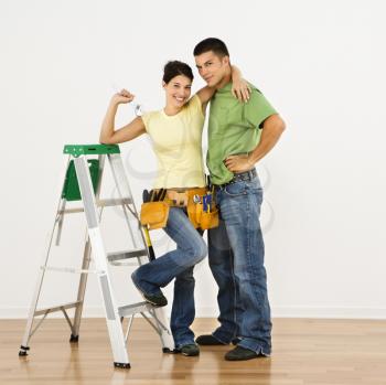 Royalty Free Photo of a Couple With Tools and a Ladder Standing in Home Smiling