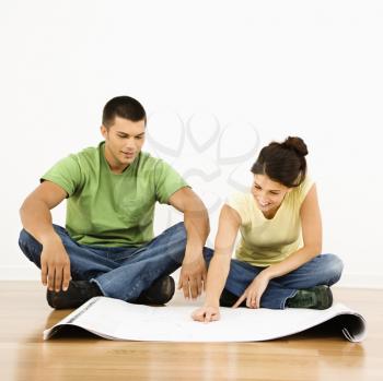 Attractive young adult couple looking at house plans.