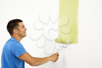 Royalty Free Photo of a Smiling Man Painting a White Wall With Green Paint