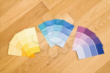 Paint color swatches grouped together by color on wood floor.