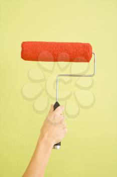 Royalty Free Photo of a Female Hand Holding a Paint Roller Dipped in Red Paint