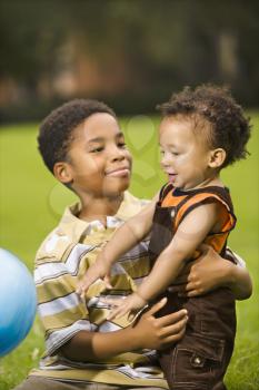 Royalty Free Photo of a Big Brother and Little Brother Playing With a Ball in a Park