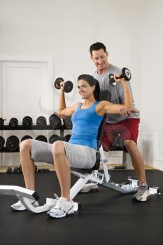 Royalty Free Photo of a Man Assisting a Woman Lifting Weights at a Gym