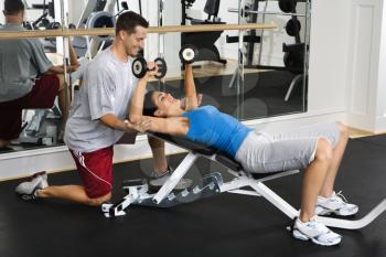 Royalty Free Photo of a Man Assisting a Woman Lifting Weights at a Gym