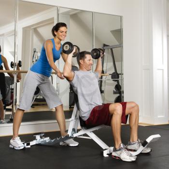 Royalty Free Photo of a Woman Spotting a Man Lifting Weights at a Gym