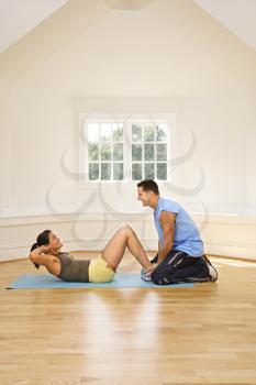 Royalty Free Photo of a Man Holding a Woman's Feet Down as She Does Sit-up Exercises.