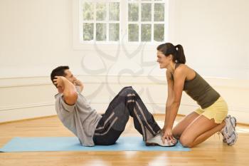Royalty Free Photo of a Woman Holding a Man's Feet Down as He Does Sit Up Exercises