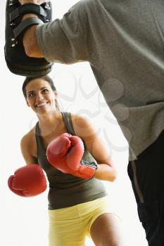 Royalty Free Photo of a Woman Wearing Boxing Gloves Hitting Training Mitts a Man is Holding