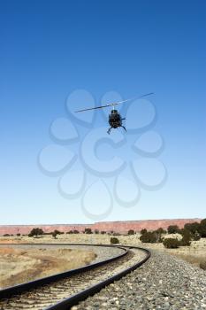Royalty Free Photo of a Helicopter Flying Over Train Tracks