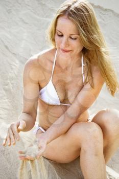 Royalty Free Photo of
a Woman Sitting on a Beach Sifting Sand Through Her Fingers