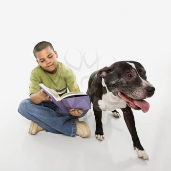 Royalty Free Photo of a Boy Reading a Book While His Dog Sits Nearby