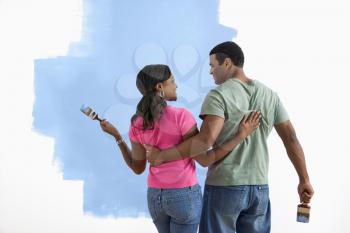 Royalty Free Photo of a Couple Standing Together Looking at a Half-Painted Wall