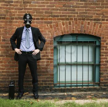 Royalty Free Photo of a Businessman Standing Next to a Brick Wall Wearing a Gas mask