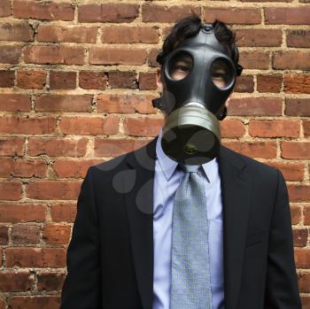 Royalty Free Photo of a Businessman Standing Next to  Brick Wall Wearing a Gas Mask