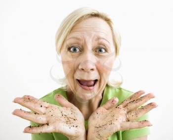 Exasperated adult blonde woman with hands covered in dirt.
