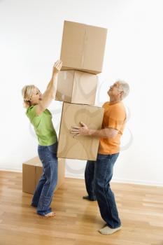 Royalty Free Photo of a Man Holding a Stack of Cardboard Boxes While a Woman Places Another One On