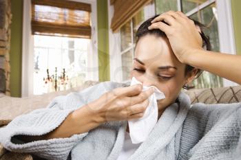 Sick young woman blows her nose into a tissue. Horizontal shot.