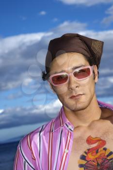 Portrait of a young man with sunglasses and headscarf at the beach. Vertical shot.