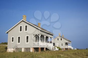 Low angle view of two identical looking beachfront homes against a backdrop of a clear, blue sky. Horizontal shot.