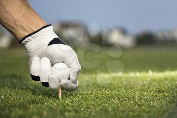 Male golfer places a golf ball and tee in the ground. Horizontal shot.