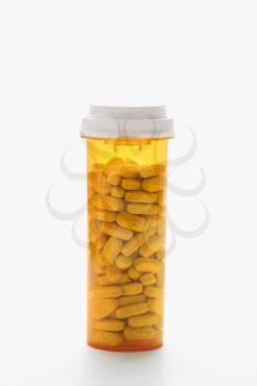 Yellow pill bottle filled with tablets against a white background. Vertical shot. Isolated on white.